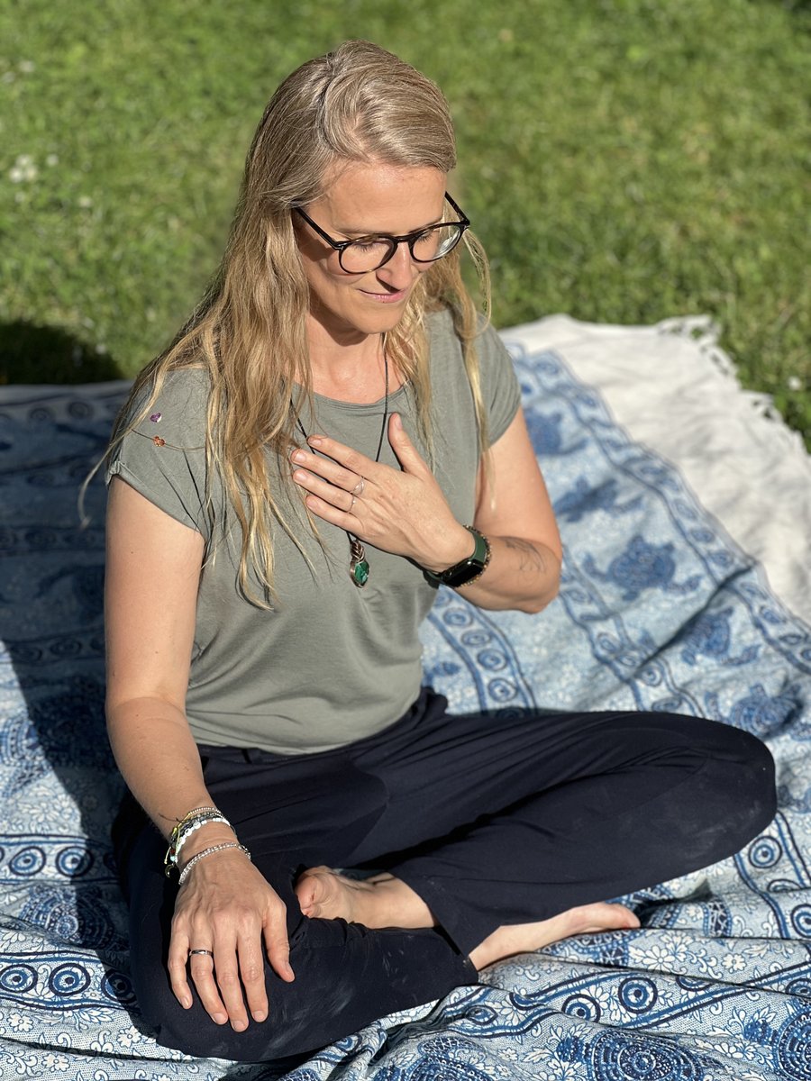 Petra Martinek, sitzend im Freien, Hand auf dem Herzen, ruhiger Moment